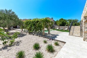 A courtyard with a pergola, stone walls, and a grassy area. - Villa Magna (Dobropoljana)
