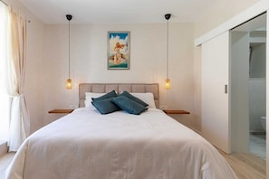 A neatly made bed with a headboard, two bedside lamps, and a painting above it. - Villa Magna (Dobropoljana)