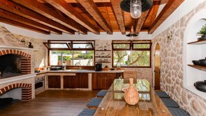Una cocina rústica con horno de ladrillo, vigas de madera, paredes de piedra y ventanas amplias.