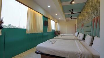 A hotel room with two beds, a ceiling fan, and a view of palm trees through the window.