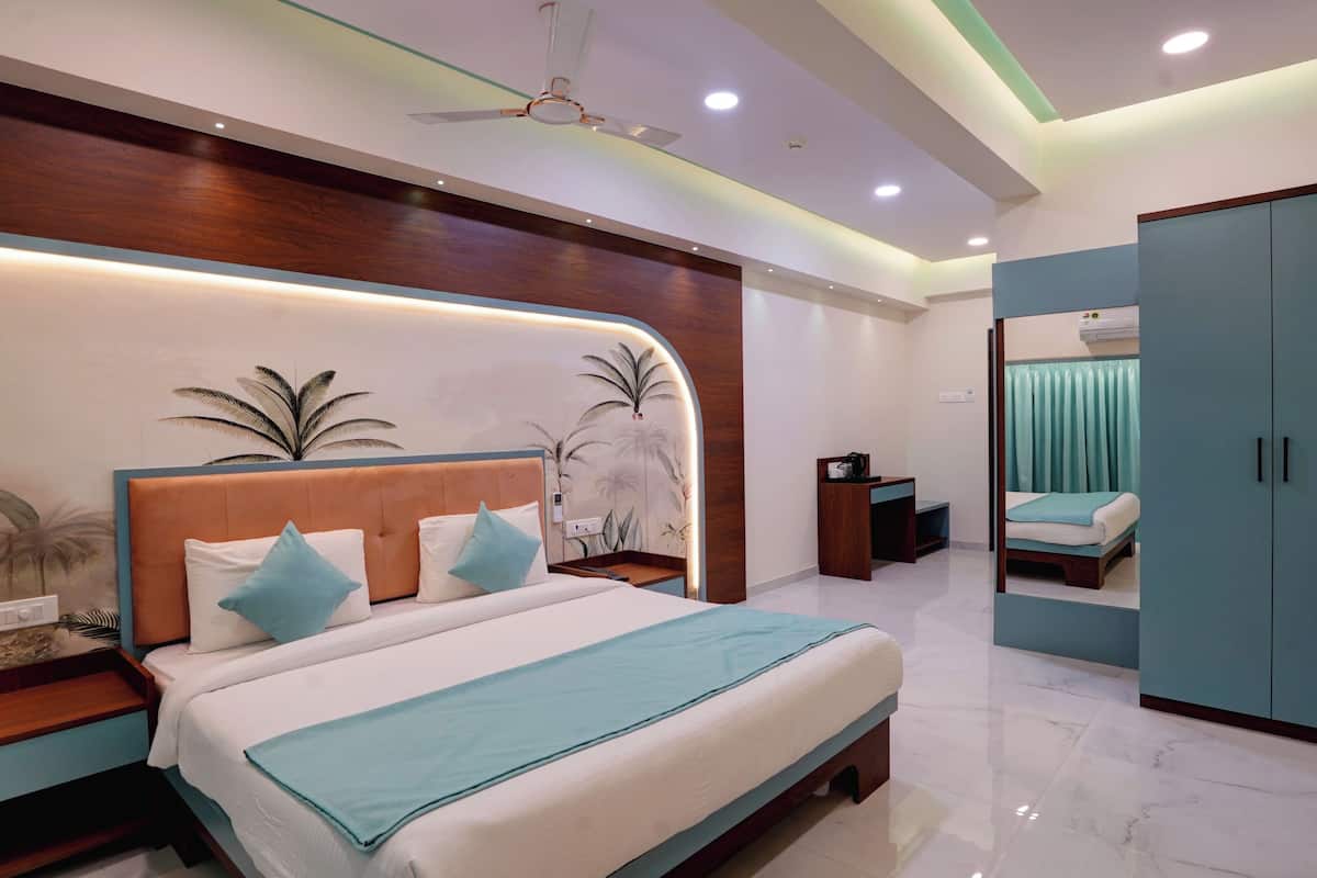 Un dormitorio moderno con cabecera curvada, una cama grande con colcha azul, una mesita de noche y un armario.