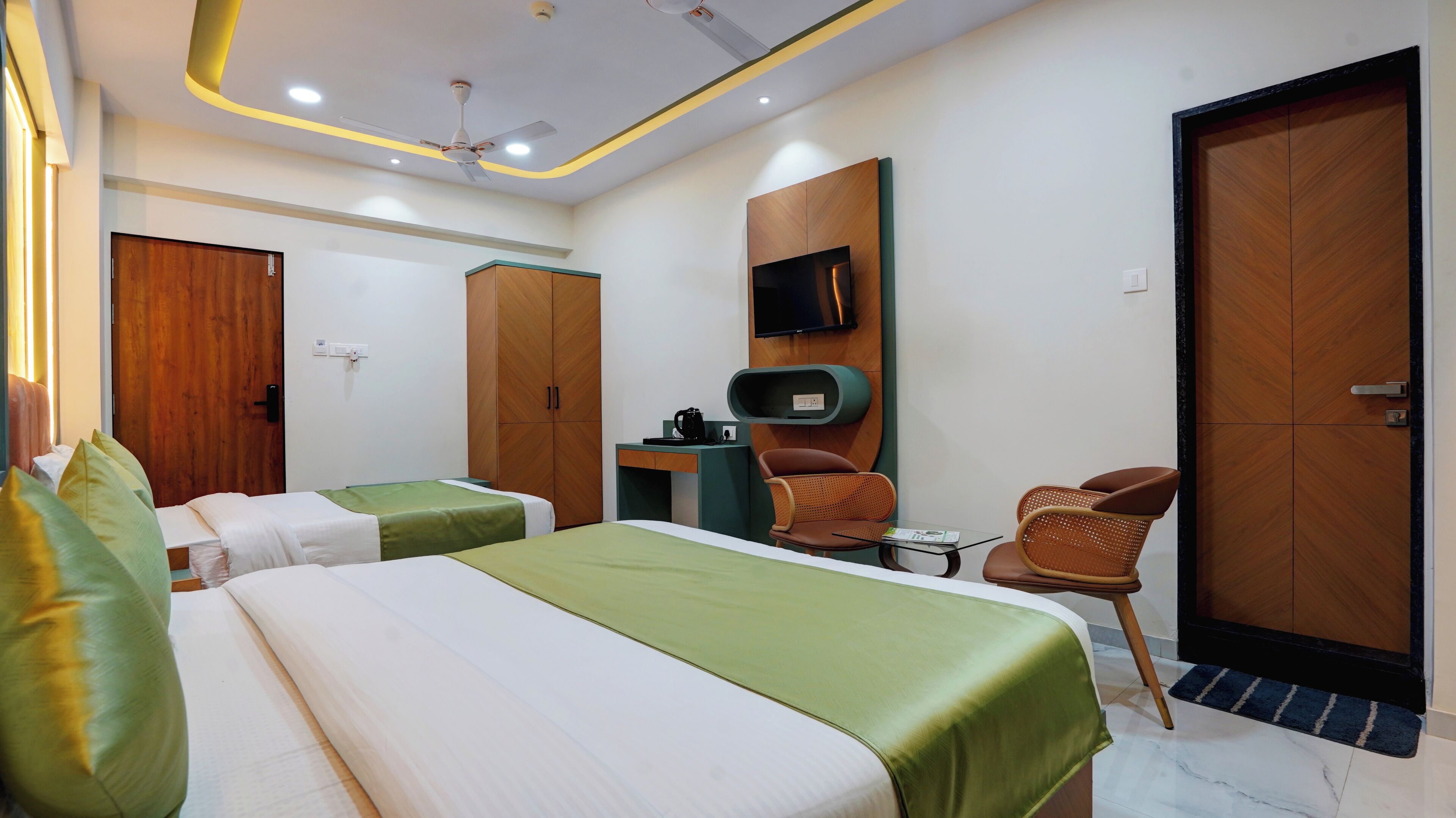 A hotel room with two beds, a desk, a chair, a TV, and a wardrobe.