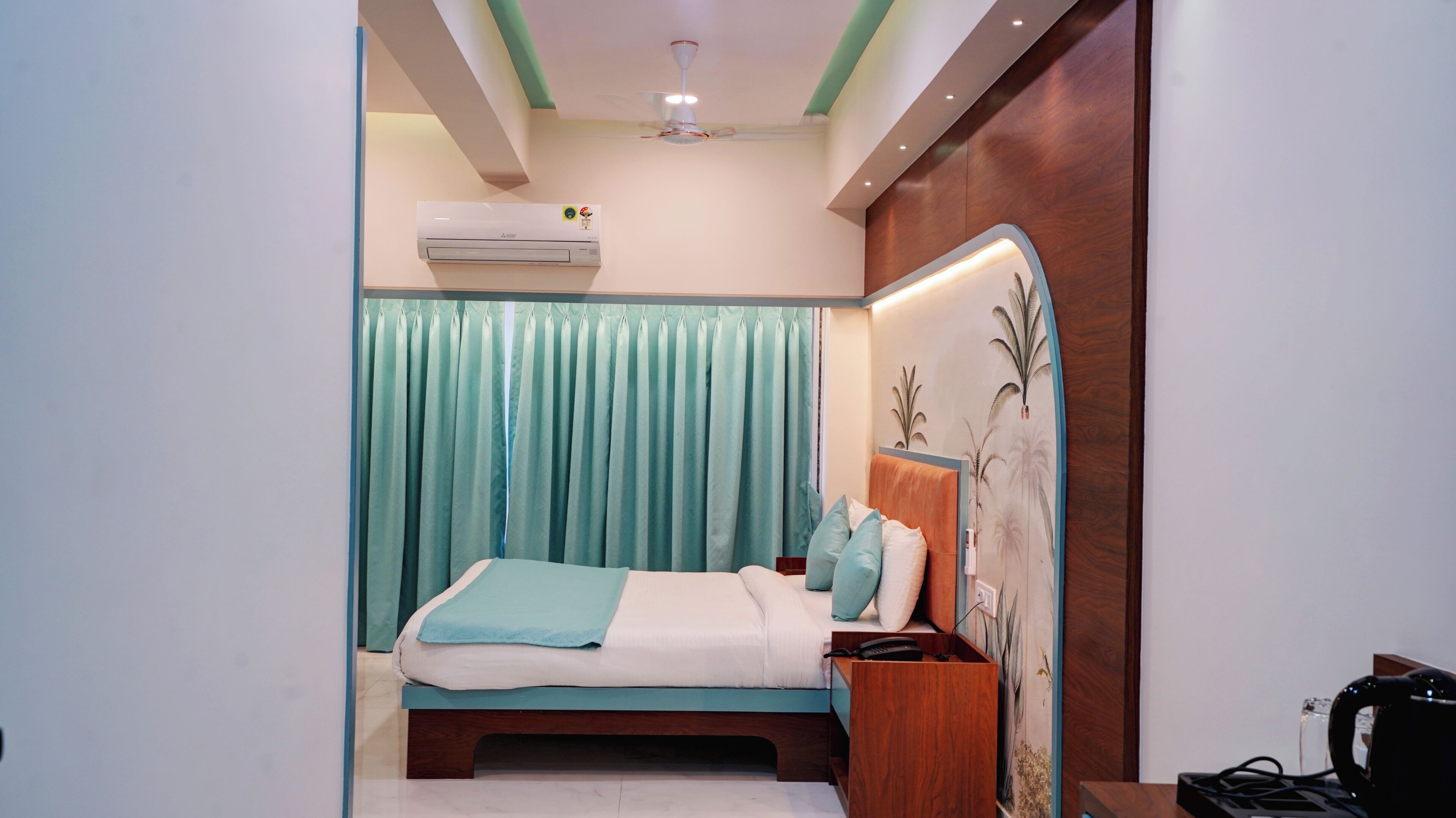Une chambre à coucher comprenant un lit, des rideaux, un ventilateur de plafond, un appareil de climatisation et un panneau décoratif mural.
