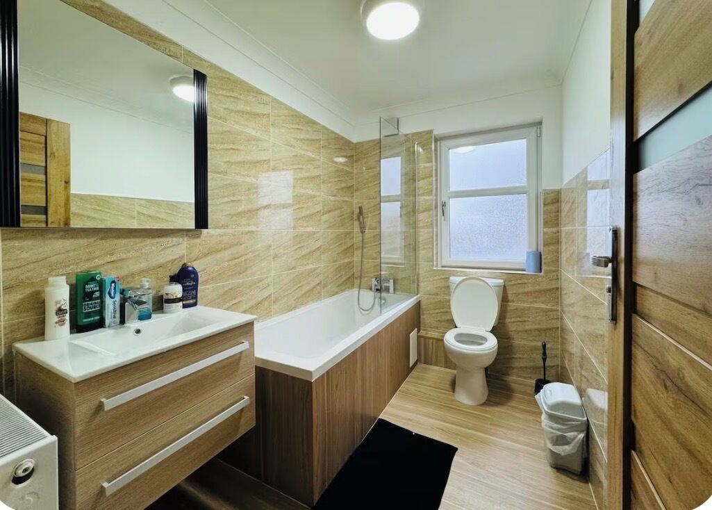 Een moderne badkamer met een houten wastafelmeubel, een bad en een toilet.