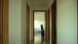 Un corridoio con porte in legno e un termosifone sullo sfondo.
