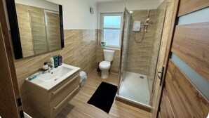 Un bagno moderno con cabina doccia in vetro, lavandino bianco e uno specchio grande.