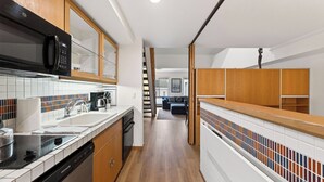 A modern kitchen with a microwave, dishwasher, and wooden cabinets. - The Traverse by Avantstay Ski-in/ski-out Condo Pool, Hot Tub Access Steps to Kt-22 (Olympic Valley)
