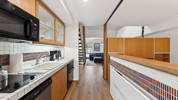 A modern kitchen with a microwave, dishwasher, and wooden cabinets. - The Traverse by Avantstay Ski-in/ski-out Condo Pool, Hot Tub Access Steps to Kt-22 (Olympic Valley)