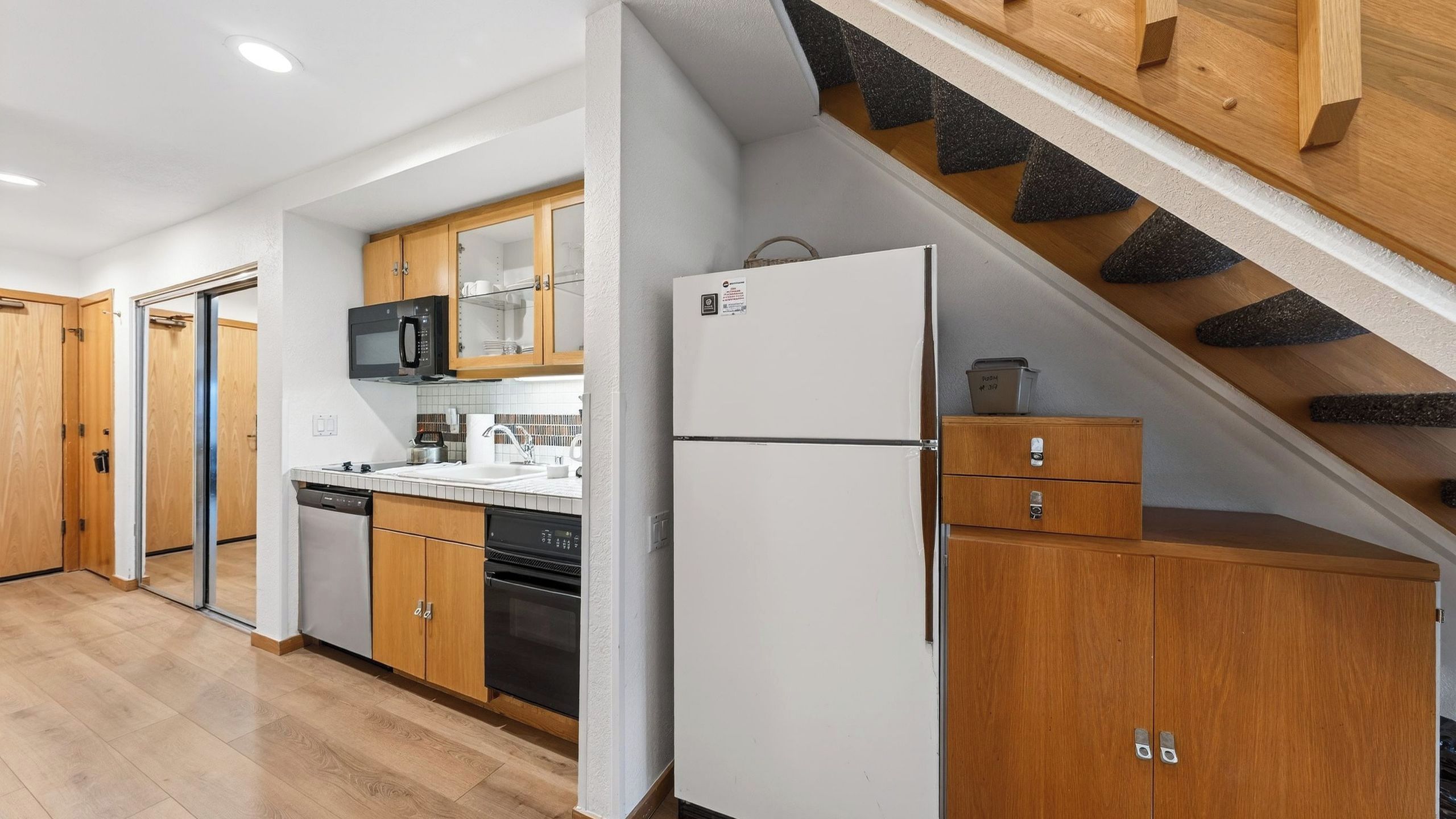Une cuisine moderne avec des meubles en bois, un réfrigérateur blanc, un four à micro-ondes et un lave-vaisselle.