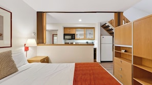 A bedroom with a bed, a nightstand, a lamp, a dresser, and a view into the kitchen. - The Traverse by Avantstay Ski-in/ski-out Condo Pool, Hot Tub Access Steps to Kt-22 (Olympic Valley)