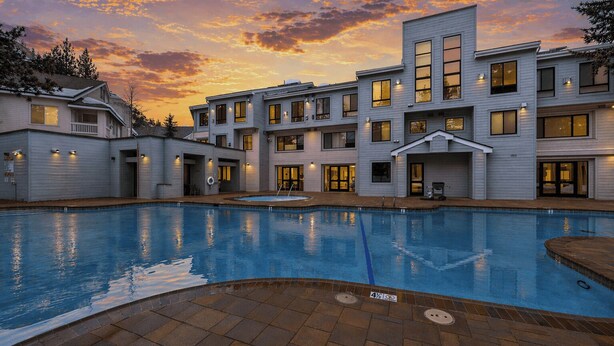 A residential building with a swimming pool, multiple windows, and a well-lit exterior. - The Traverse by Avantstay Ski-in/ski-out Condo Pool, Hot Tub Access Steps to Kt-22 (Olympic Valley)