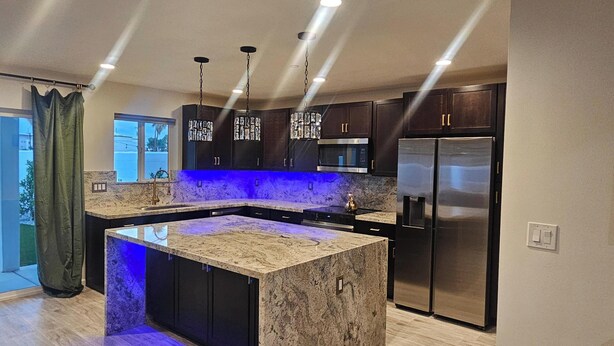 A modern kitchen with dark cabinetry, stainless steel appliances, and a central island with a marble countertop. - Scottsdale Oldtown Paradise - New Home with 4 bedrooms and 3 bath (Scottsdale)
