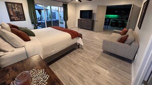 A modern bedroom with a large bed, a sofa, a TV, and a balcony with a bar area. - Scottsdale Oldtown Paradise - New Home with 4 bedrooms and 3 bath (Scottsdale)
