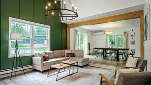 A living room with a sectional sofa, a coffee table, and a dining area with a table and chairs. - Hot Tub + Sauna Escape | Game Room, Fire Pit, Sleeps 14 (Tobyhanna)
