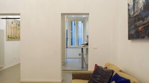 Uma sala de estar com sofá, um quadro e uma porta que dá para um banheiro.