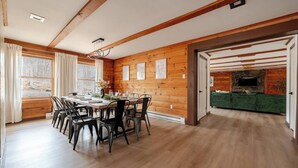 Un comedor con mesa y sillas de madera, una chimenea y un sofá verde en la habitación contigua.