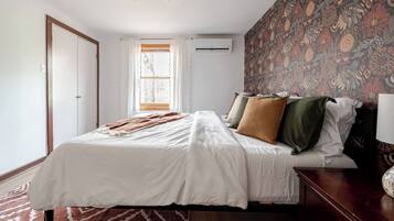 Un dormitorio con cama, ventana con cortinas, pared con diseño y lámpara de techo.