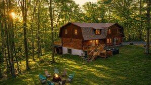 Una cabaña de troncos con terraza, mobiliario exterior y un brasero.