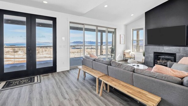A spacious living room with a large gray sectional sofa, a wooden bench, and a fireplace. - The Lazy Days Getaway at Bear Lake with Ideal Beach Access (Garden City)