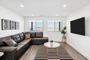 Una sala de estar moderna con un sofá modular, una mesa de centro redonda y un televisor de pantalla plana grande montado en la pared.