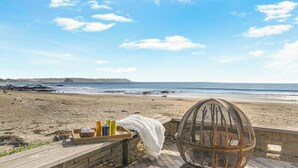A beach view with a wooden deck, a wicker chair, and a tray with drinks and snacks. - The Jamie by Avantstay Oceanfront Stay + Firepit + Chef's Kitchen + Near Morro Bay (Cayucos)