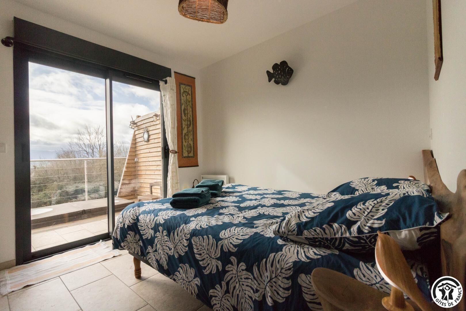 Una camera da letto con un letto grande, una porta scorrevole in vetro su un balcone e vista sull'esterno.
