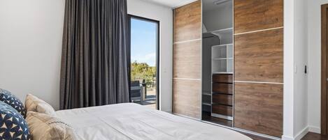 A bedroom with a bed, a sliding door closet, and a view of the outdoors.