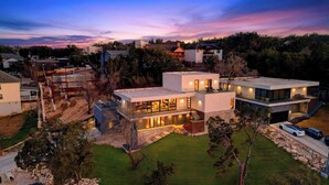 A modern multi-story house with a spacious outdoor area, a garage, and a driveway. - Hunters Estate by Avantstay Design-forward Hillside Home Private Pool + Firepit Close to Lake Travis + Downtown Austin (Austin)