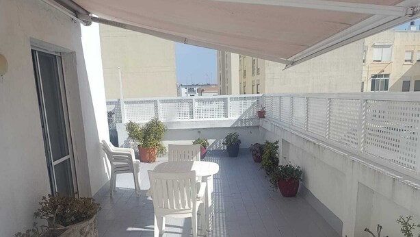 A rooftop terrace with a table and chairs, potted plants, and a white fence. - Penthouse with terrace (San Fernando)