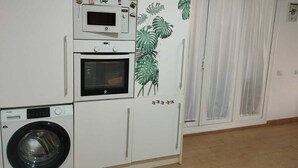 A compact kitchen with a microwave, oven, and washing machine. - Penthouse with terrace (San Fernando)