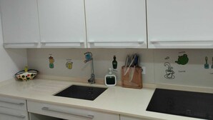 A kitchen with white cabinets, a sink, and a countertop with various kitchen items and illustrations. - Penthouse with terrace (San Fernando)