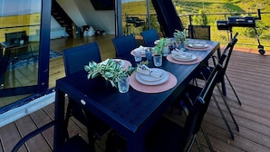 Uma sala de jantar com mesa posta para quatro pessoas, com vista para uma paisagem deslumbrante.