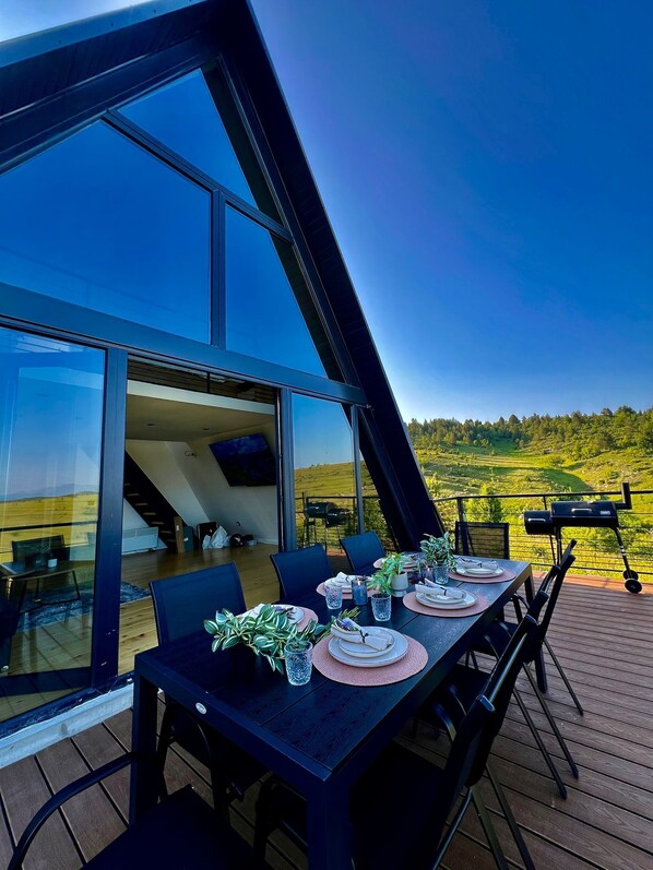 A dining area with a table set for four, overlooking a scenic landscape.