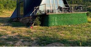 Um edifício moderno com telhado inclinado, janelas amplas e um pequeno terraço ao ar livre.