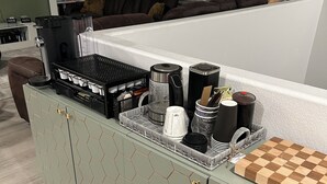 A kitchen with a hexagonal-patterned cabinet, a coffee maker, a kettle, and a checkered cutting board on the counter. - Bri’s Place Cozy 2BR Home Near Nellis AFB & Speedway (Las Vegas)