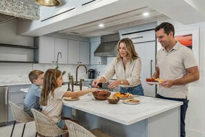 A modern kitchen with a central island, stainless steel appliances, and a large window. - Beachfront Bliss - Outdoor Pool - Sleeps 6 (Belleair Beach)