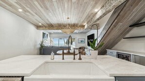 A modern kitchen with a large island, stainless steel appliances, and a view of the ocean. - Beachfront Bliss - Outdoor Pool - Sleeps 6 (Belleair Beach)
