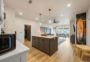 A modern kitchen with a central island, wooden flooring, pendant lighting, and a ceiling fan. - Private Pool, Dock, Movie Room on Lake Hamilton (Hot Springs)