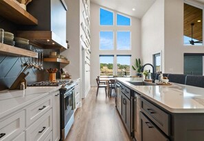 A modern kitchen with a central island, built-in appliances, and a large window offering a view. - Private Pool, Dock, Movie Room on Lake Hamilton (Hot Springs)
