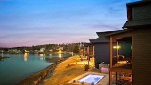 Ein Anwesen am Wasserufer mit Pool, Sitzgelegenheiten im Freien und einer überdachten Terrasse.