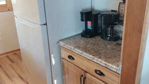 Une cuisine équipée d’un réfrigérateur LG blanc, d’une machine à café, de meubles de rangement en bois et d’un plan de travail en granit.