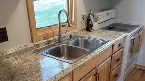 Une cuisine dotée de plans de travail en granit, d’un évier en acier inoxydable, de meubles en bois, d’un four à micro-ondes et d’une cuisinière.