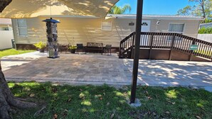 A patio with a stone floor, outdoor furniture, and a pergola. - Lovely 3-bedroom mobile home with AC in charming Largo (Largo)