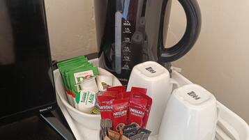 A tray with a coffee maker, a TV, and various beverage packets.