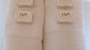 Two folded towels with 'LUX BEAUTY SOAP WITH MOISTURISERS' labels, placed on a bed. - BRISTOL HOTEL (Bristol)
