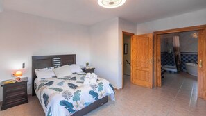 A bedroom with a bed, nightstand, and a bathroom visible through an open door. - Casa Luis Canillas de Aceituno by Ruralidays (Málaga)