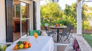 Eine Terrassengruppe im Freien mit einem runden Tisch, Stühlen und einer Obstschale.