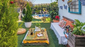 A cozy outdoor seating area with a pool, surrounded by lush greenery and potted plants. - Casa Luis Canillas de Aceituno by Ruralidays (Málaga)