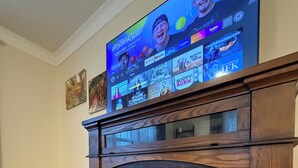 A living room with a fireplace, a television mounted above it displaying various streaming services, and a patterned rug on the floor. - Peaceful 1-bedroom apartment with AC in vibrant Minneapolis (Minneapolis)