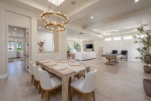 A spacious living area with a dining table, sofas, and a TV. - Casa Caliza at PGA West | Nicklaus Fairway Views (La Quinta)